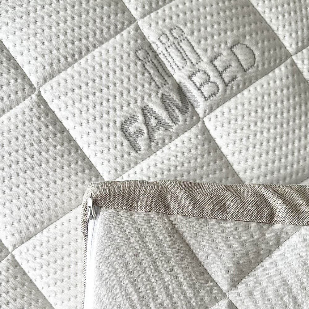 Close-up van de gewatteerde witte hoes van de topmatras met ingeweven FAMBED-logo
