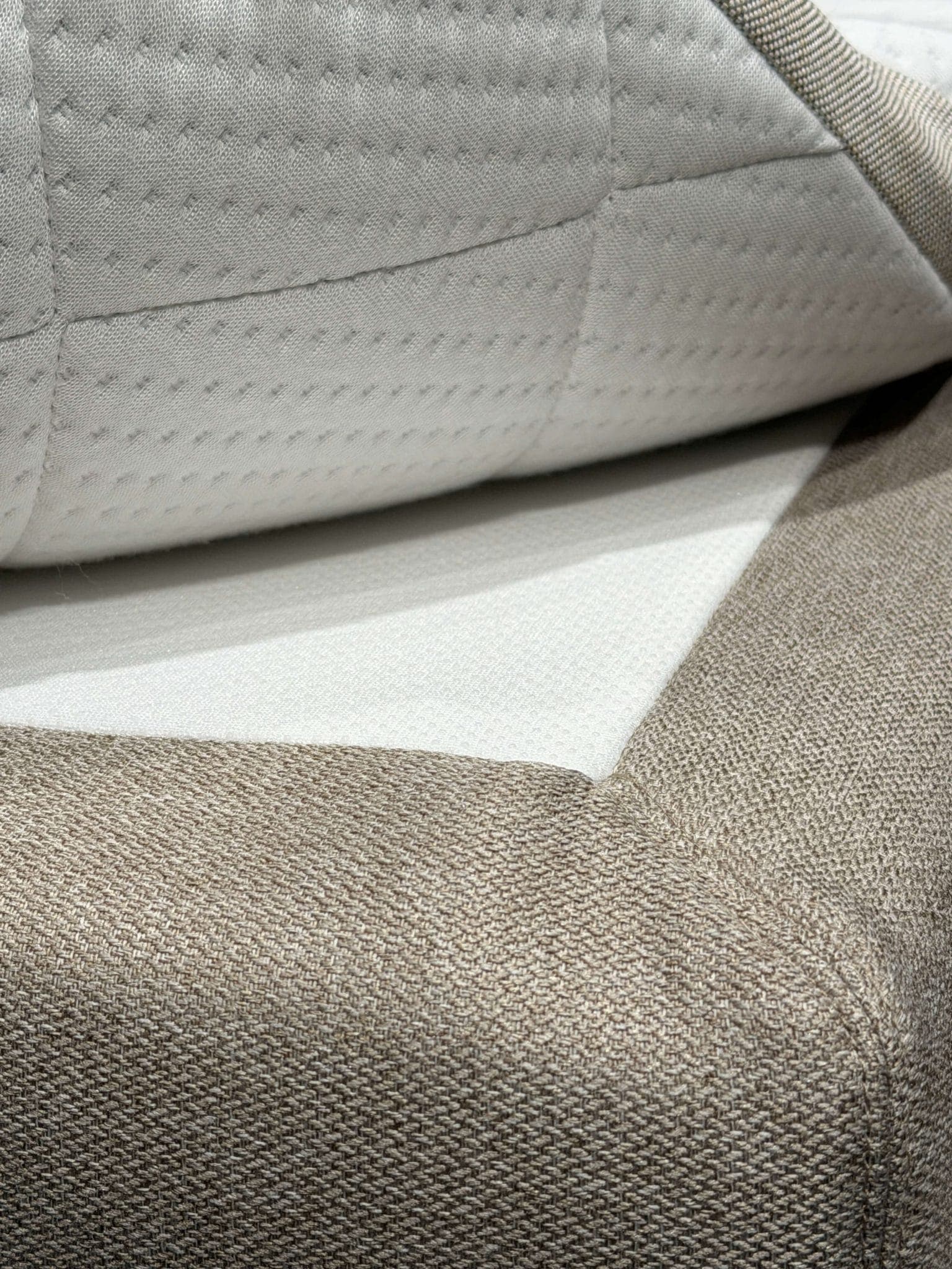 Opgetilde hoek van de topmatras, waardoor de antisliplaag tussen de topmatras en de bedhoes zichtbaar is