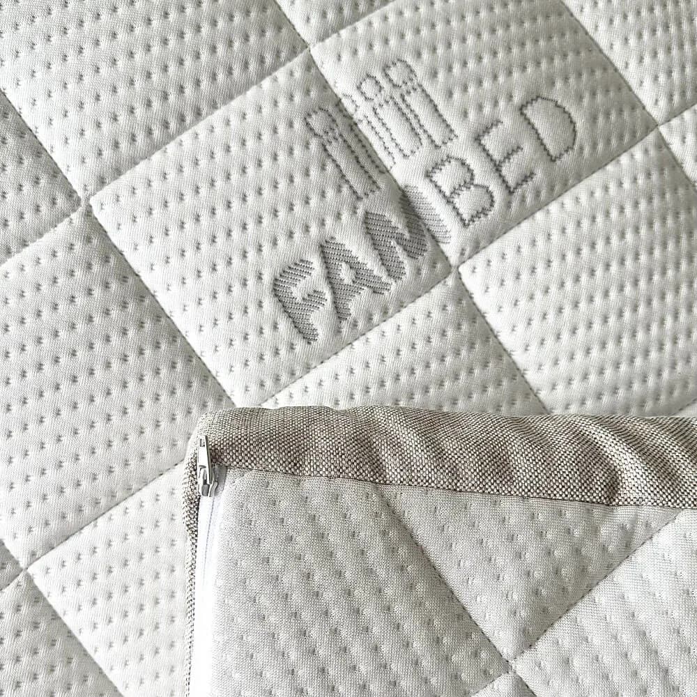 Close-up van de gewatteerde witte hoes van de topmatras met ingeweven FAMBED-logo