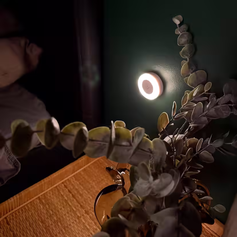 Ronde borstvoedingslamp die 's nachts een gedempt licht op de muur naast het bed laat schijnen